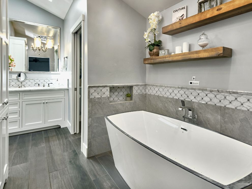 View of a modern bathroom renovation with a large tub, sink, and floating shelves