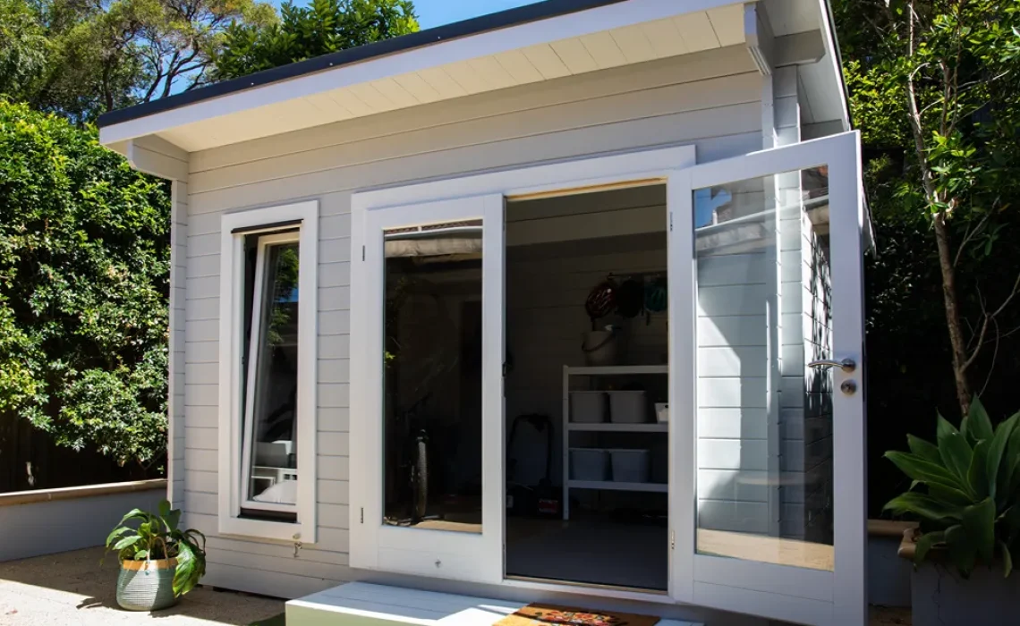 A housing unit with the door open and trees around it and behind it.