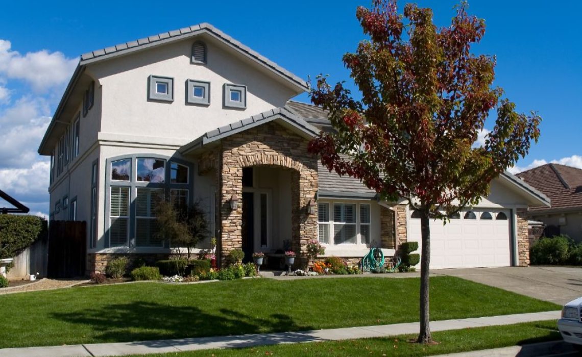 A view of the front exterior of a home. There is a tree in front of the home.
