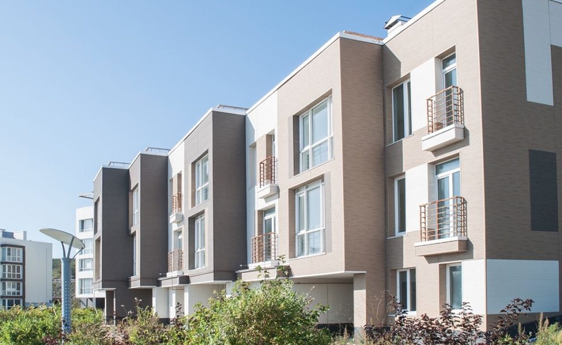A group of buildings with trees near them. The sky is clear.