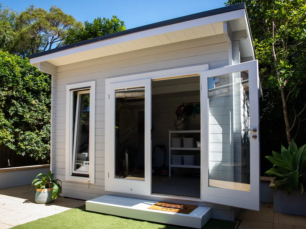 A housing unit with the door open and trees around it and behind it.