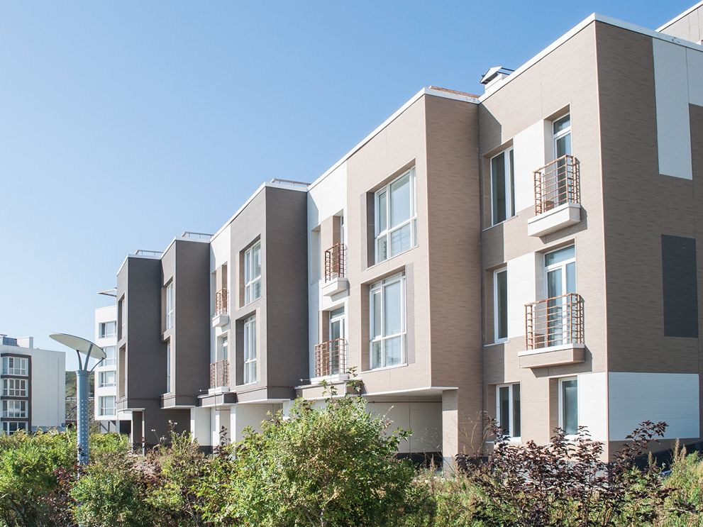 A group of buildings with trees near them. The sky is clear.